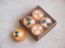 Load image into Gallery viewer, &quot;Orange Blossom&quot; Tealight Set - Unscented orange soy candles decorated with white wax flowers and green wax leaves.