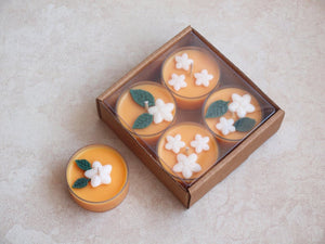 "Orange Blossom" Tealight Set - Unscented orange soy candles decorated with white wax flowers and green wax leaves.