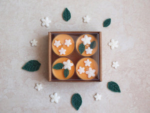 "Orange Blossom" Tealight Set - Unscented orange soy candles decorated with white wax flowers and green wax leaves.